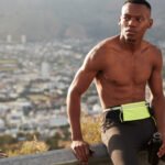 Countryside healthy active lifestyle concept. Concentrated ethnic man with muscular body, holds sport bottle filled with water, takes break after sprinting, ready for running marathon, joggs outside