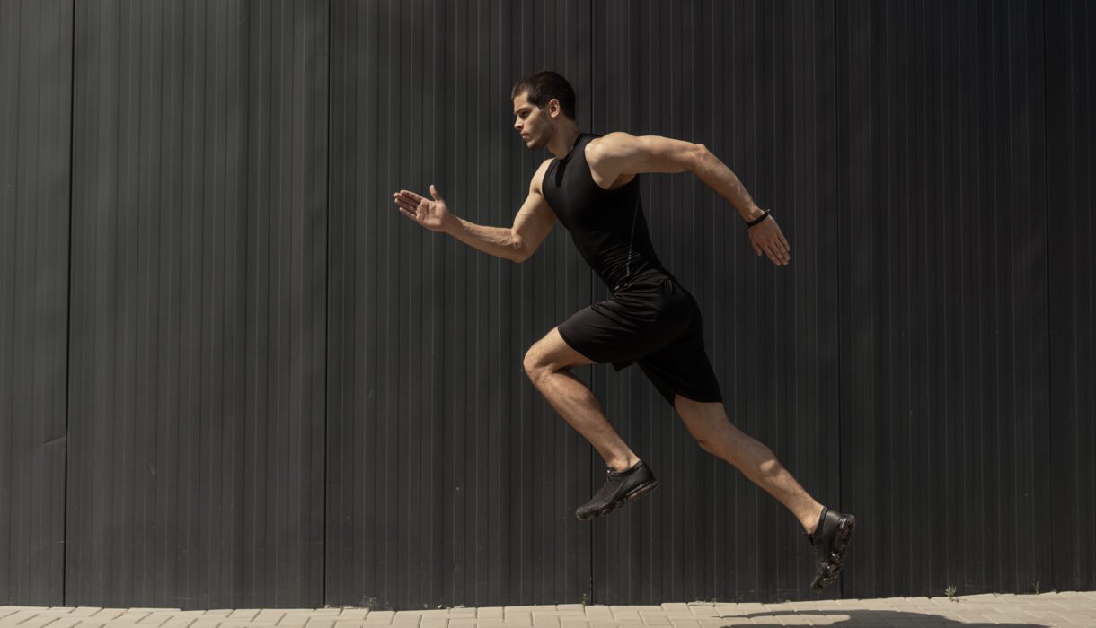 A side view shot of a fit young, athletic man jumping and runnin