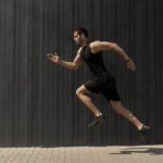 A side view shot of a fit young, athletic man jumping and runnin